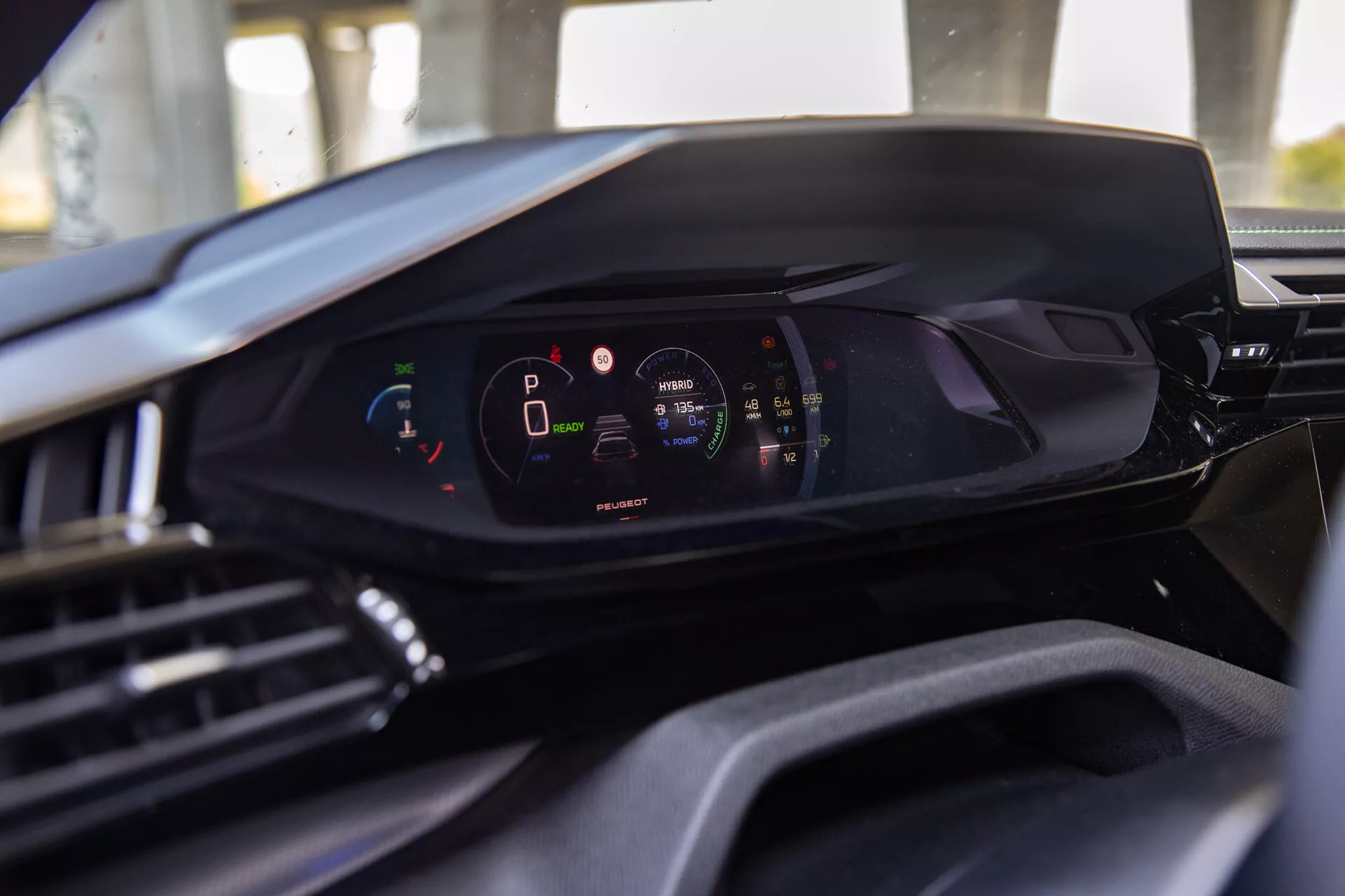 Pogled na notranjost Peugeota 408 2023, ki prikazuje sodobno digitalno armaturno ploščo iz perspektive voznikovega sedeža, poudarjajoč digitalni instrumentni zaslon z vozilom v parkirnem načinu in visoko raven napolnjenosti baterije