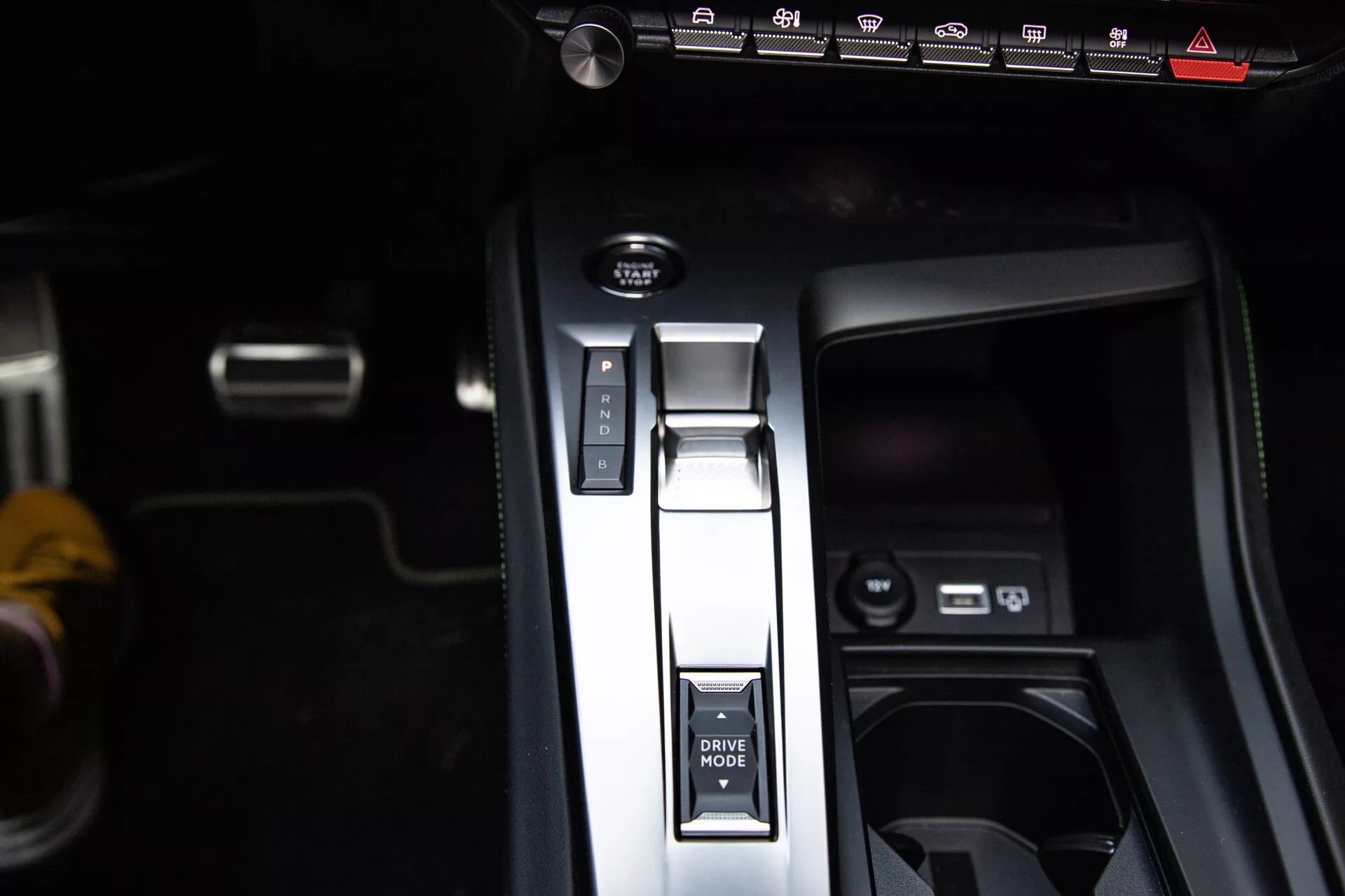 Podroben pogled na sredinsko konzolo Peugeot 408 2023 z ročico prestave v parkirnem položaju, gumbom DRIVE MODE, elektronsko ročno zavoro in USB vrati, ki predstavljajo sodobno notranje oblikovanje.