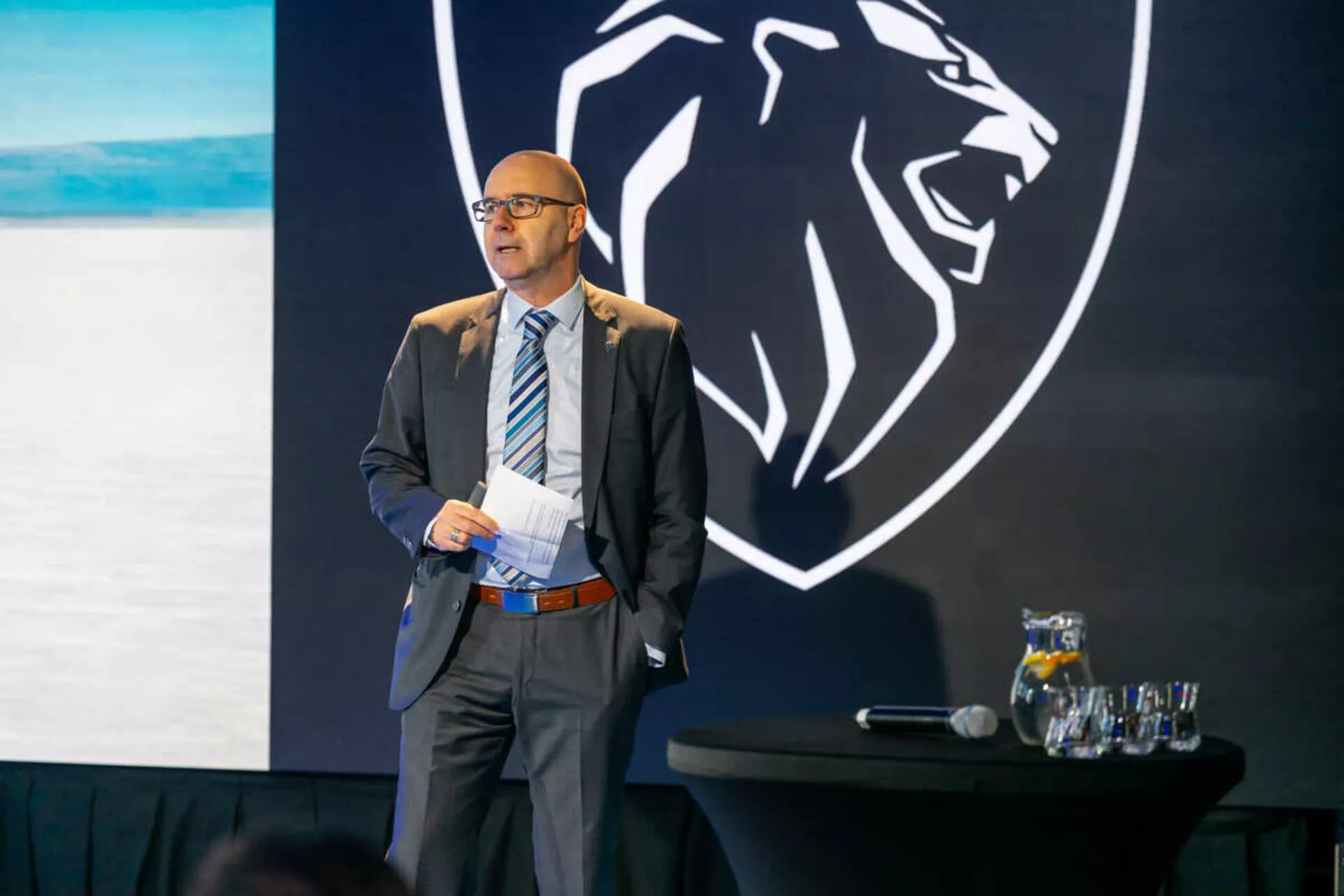Profesionalni govornik predstavlja pred ozadjem z logotipom glave tigra, ki verjetno predstavlja znamko, Peugeot 408 ali kateri koli avto ni viden
