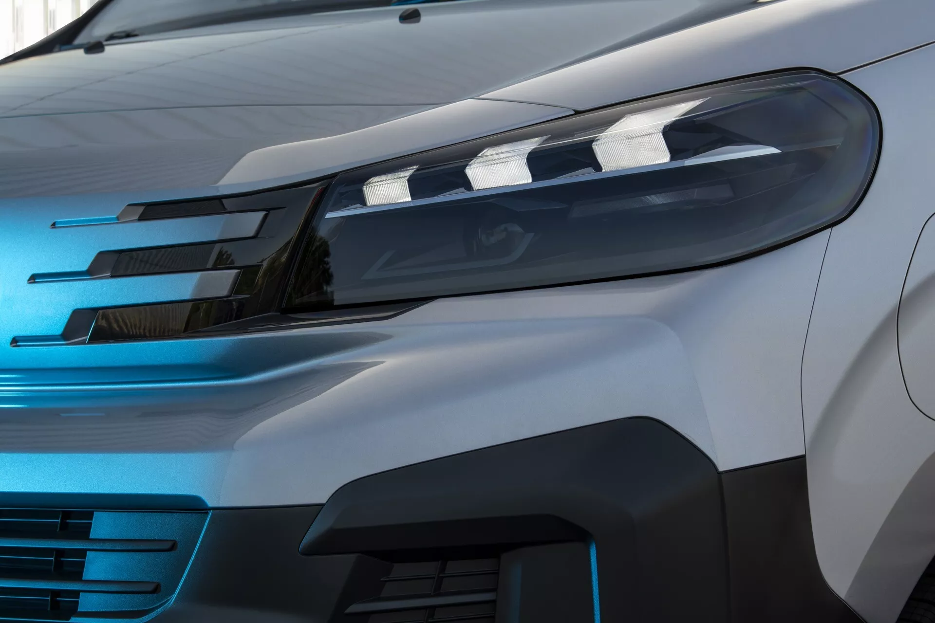 Detaljni prikaz elegantne LED prednje svetilke in delnega sprednjega žara Peugeot Expert 2024 po prenovi, vzeto iz srednje višinske stranske perspektive