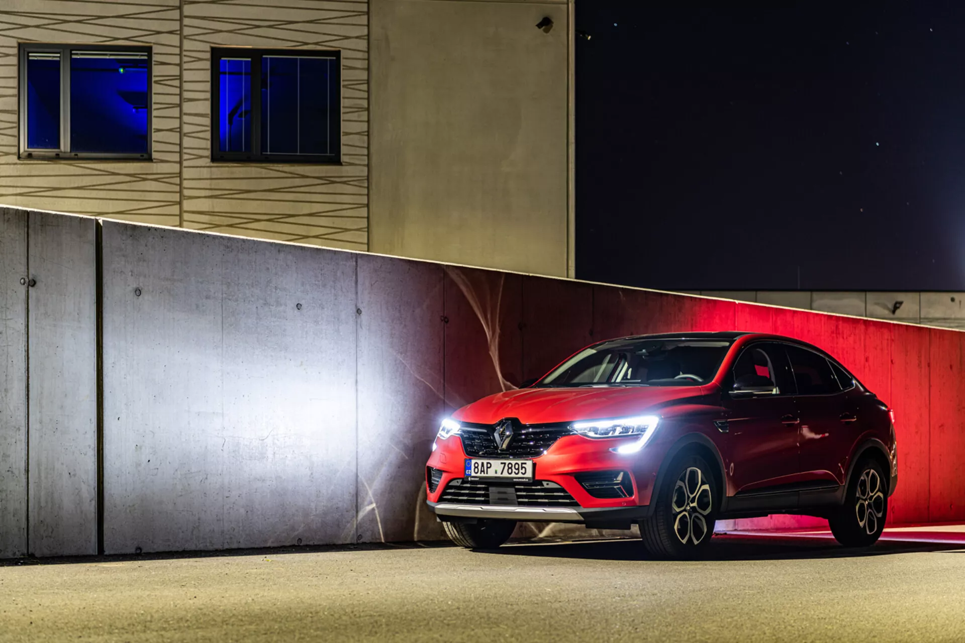 Športni hatchback Renault Arkana 2021 parkiran ponoči, ki prikazuje LED žaromete, sprednjo rešetko in lita kolesa pod umetno razsvetljavo