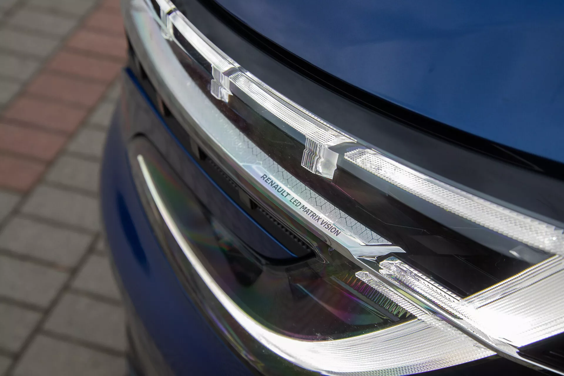 Podroben pogled na sprednji del Renault Austral 2022, ki prikazuje LED žaromet in kromirano masko z značko proizvajalca, poudarjajoč njegov sodobni dizajn in sofisticirano tehnologijo razsvetljave.