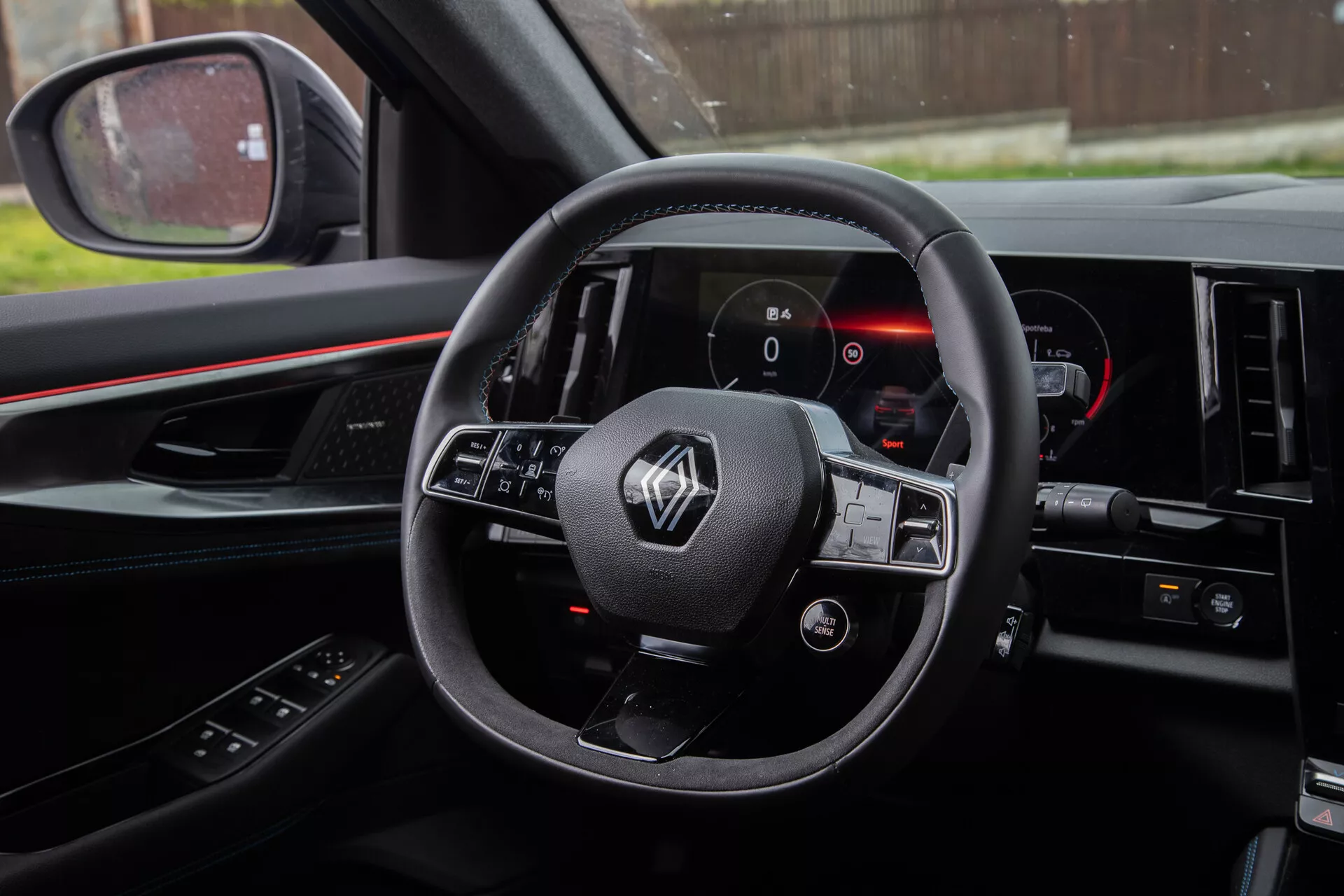 Notranji posnetek Renault Austral 2022 iz perspektive voznika, ki prikazuje volan z nameščenimi kontrolami, digitalno instrumentno ploščo in del sredinske konzole.