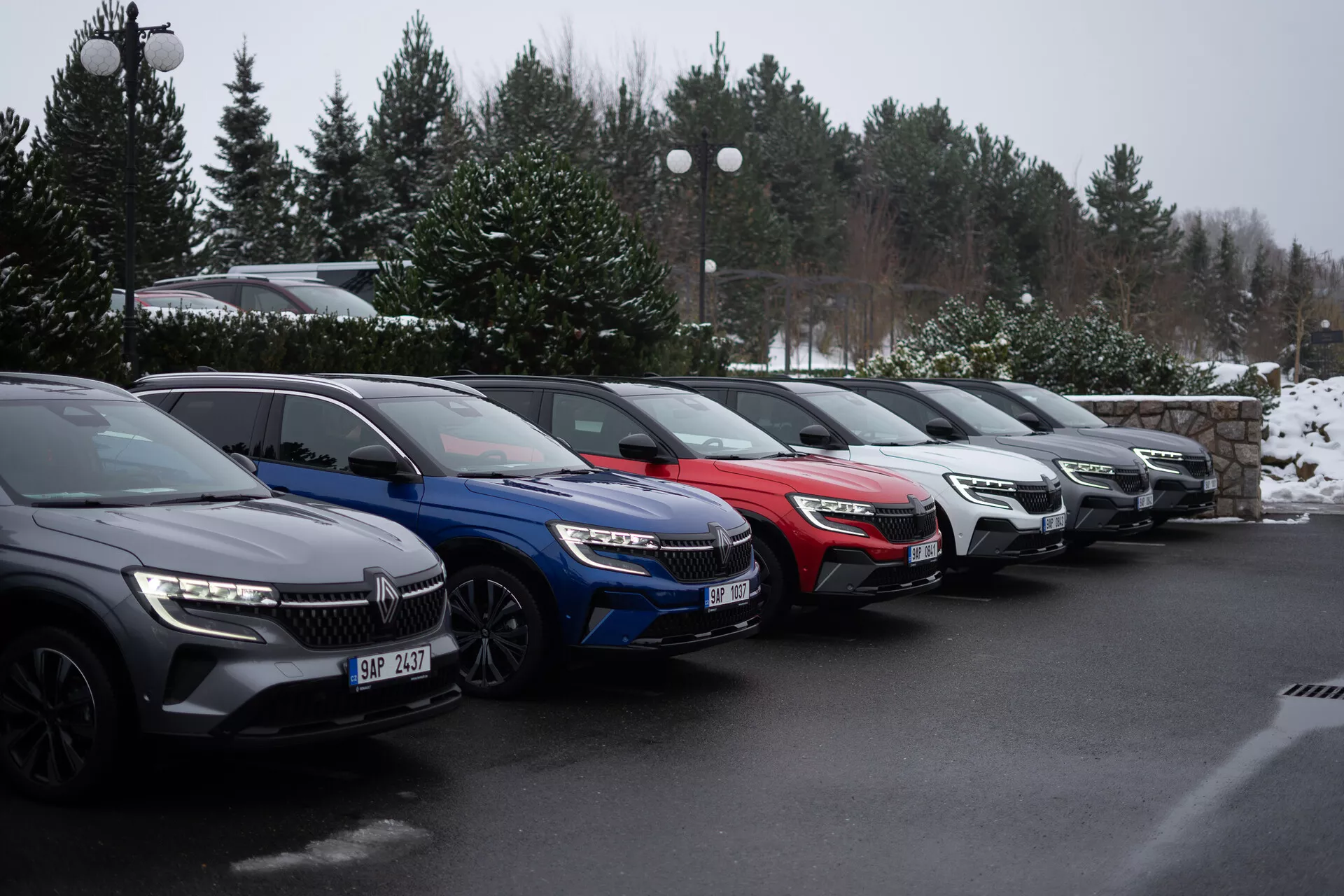 Postavitev petih avtomobilov Renault Austral 2022, parkiranih pod kotom 45 stopinj na zimskem parkirišču, predstavlja modele v temno sivi, modri, rdeči, srebrni in sivi barvi, z LED žarometi in modernimi sprednjimi rešetkami