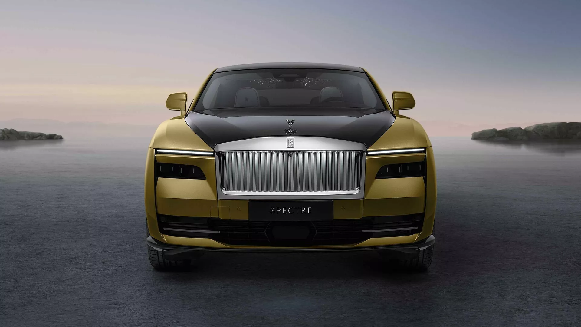 Sprednji pogled na Rolls-Royce Spectre 2023 s poudarjeno rešetko, emblemom, LED žarometi in kovinskim zaključkom z naprednimi funkcijami na mirnem ozadju