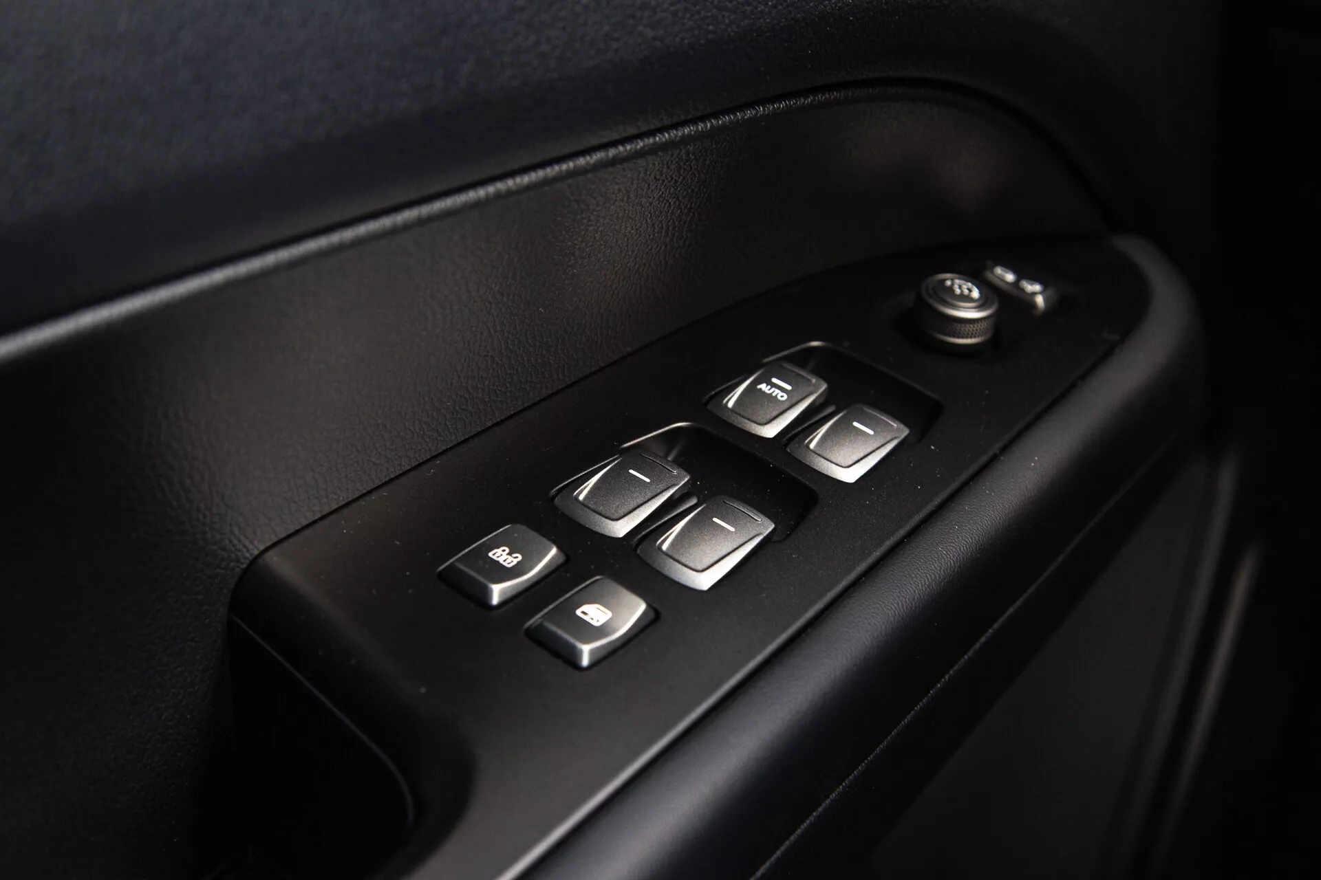Podroben pogled na notranje kontrole vrat SsangYong Musso 2022, ki prikazuje električne nastavitve oken in ogledal, osvetljene gumbe za lažjo uporabo, v visokokakovostnem, ergonomskem dizajnu