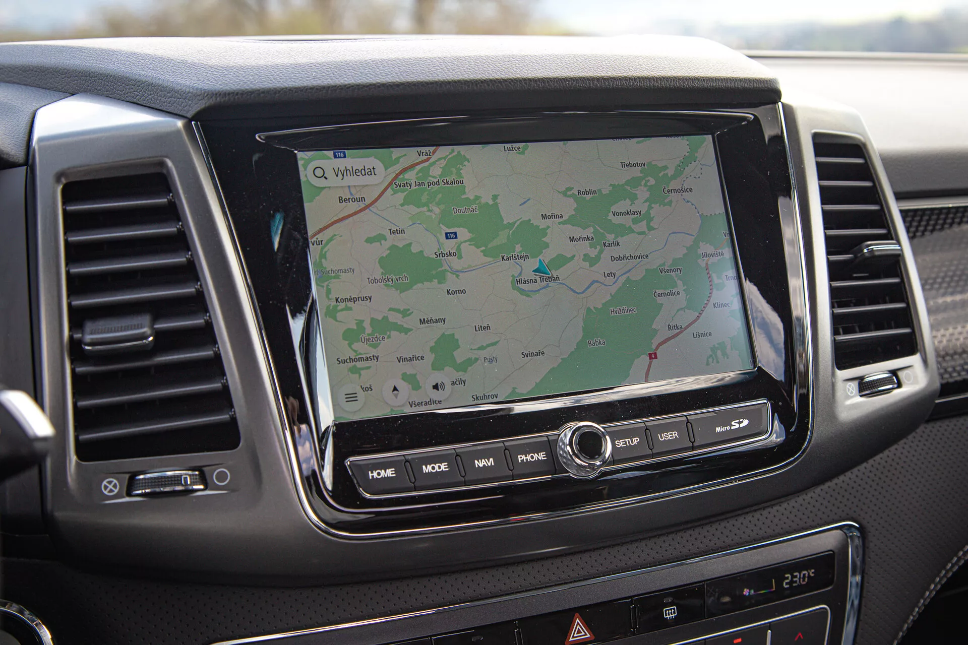 Armaturna plošča SsangYong Musso 2022 prikazuje zaslon na dotik z infotainment sistemom z GPS navigacijo, zračniki in kontrolne gumbe, pogled iz perspektive sopotnika.