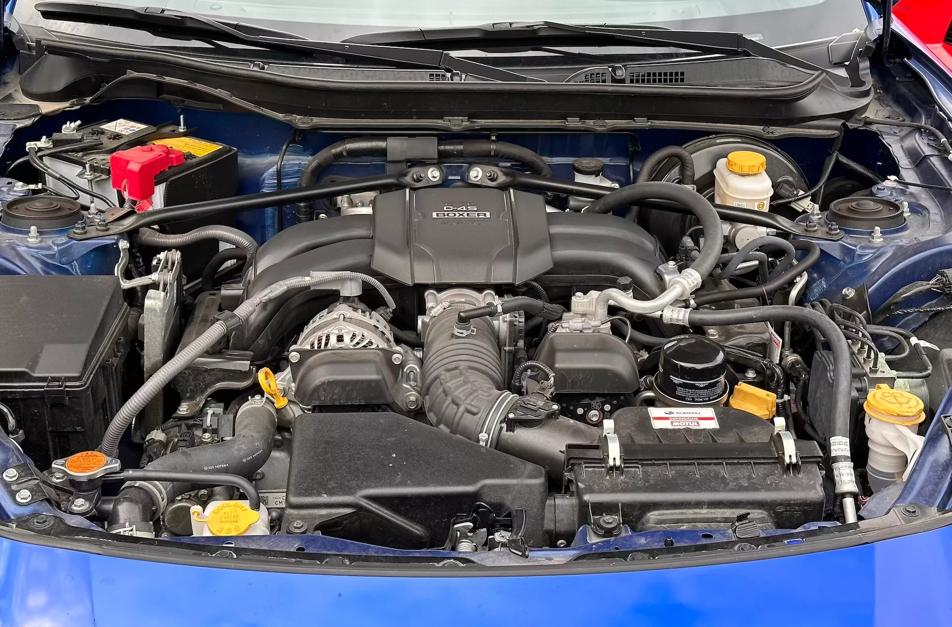 Podroben pogled na motorni prostor Subaru BRZ 2023 z motorjem BOXER, baterijo, rezervoarji za tekočine in sistemom za dovod zraka