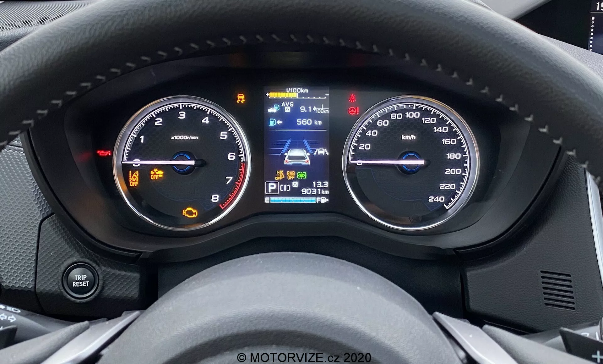 Povečan notranji pogled na instrumentno ploščo Subaru Forester 2020 z voznikove perspektive, ki prikazuje analogni tahometer z iglo nad 0 vrt./min., digitalni zaslon z navigacijskim zemljevidom, poln kazalnik goriva in funkcije za pomoč vozniku, poleg analognega merilnika hitrosti, ki meri do 260 km/h, kar kaže, da vozilo miruje. Sodobna zasnova z vgrajenimi digitalnimi zasloni.