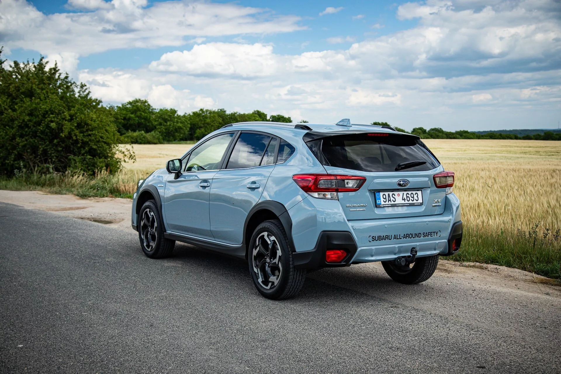 Svetlo modri kompaktni SUV Subaru XV 2021, fotografiran z zadnjega tričetrtinskega kota, ki poudarja desno stran vozila, dinamično držo na tlakovani cesti z jasnim pogledom na zadnji spojler, zlitinska kolesa, LED zadnje luči, značko modela, enojnim izpušnim koncem in potencialne tehnološke funkcije