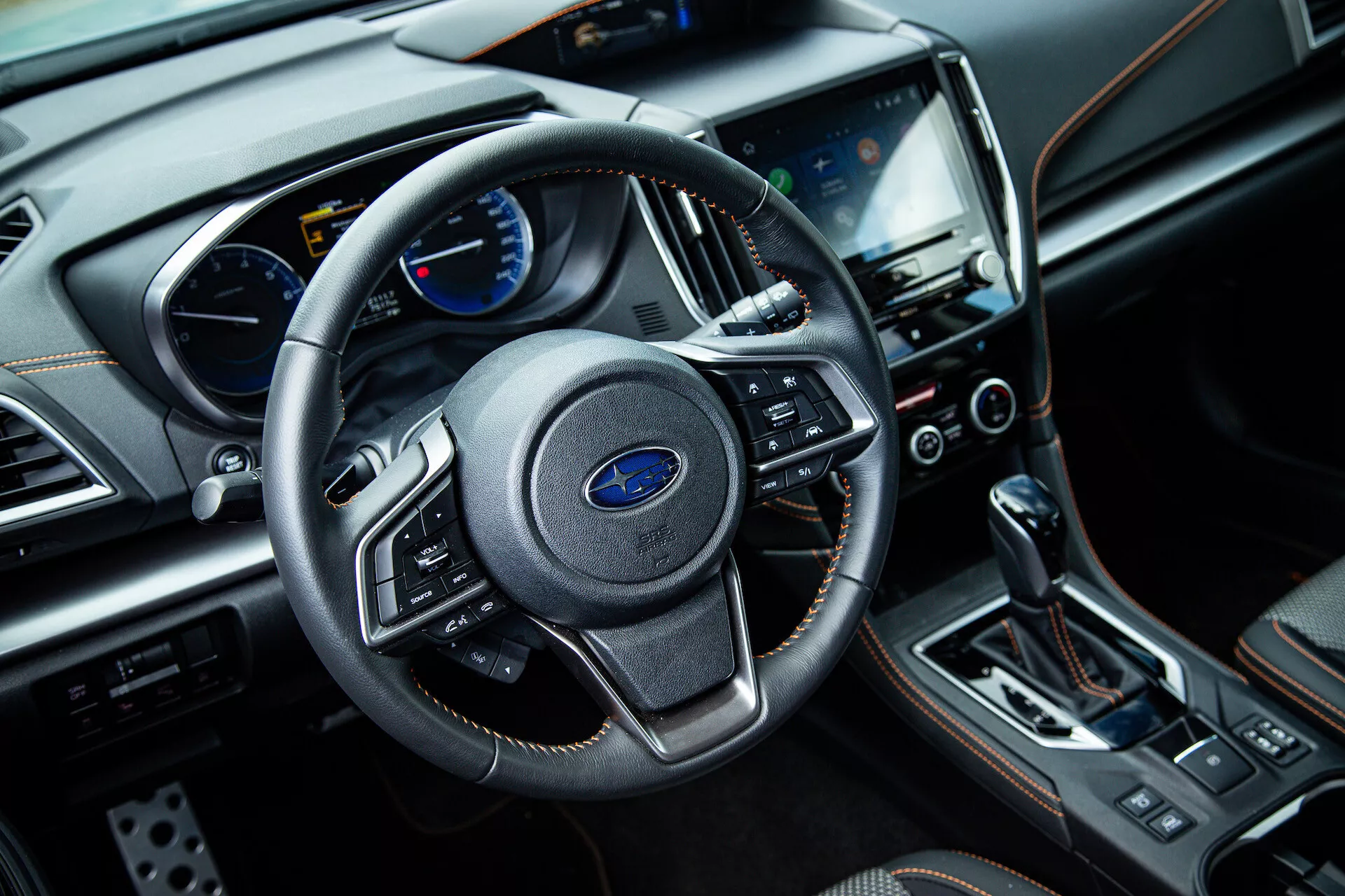 Notranjost Subaru XV 2021 iz perspektive sovoznikovega sedeža prikazuje triskov volan z večfunkcijskimi kontrolami, instrumentno ploščo z analogno in digitalno prikazovanjem na armaturni plošči, centralni zaslon na dotik infotainment sistema, gumbi za nadzor klime, avtomatsko prestavno ročico in luksuzne zaključne materiale, vključno z usnjem in kromiranimi akcenti.