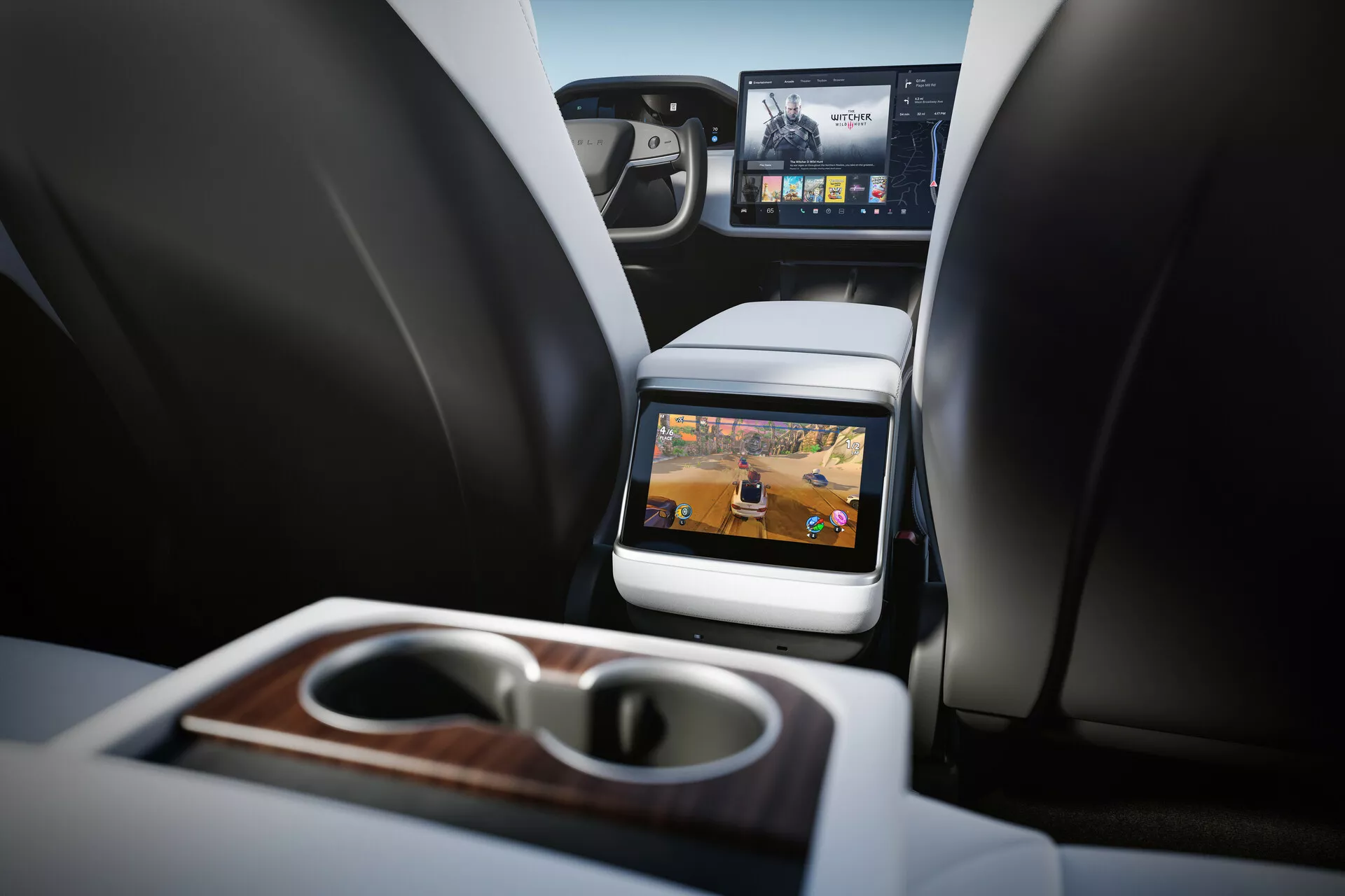Pogled na notranjost Tesla Model S 2016 (prva generacija facelift) z osredotočanjem na zadnji potniški prostor. Perspektiva s pogledom na višini zadnjih sedežev, ki prikazuje dva prednja sedeža z vzglavniki, sredinsko konzolo in vgrajen zaslon na zadnji strani prednjega sedeža. Tehnologija zabave za zadnje sedeže z vidno aktivnim zaslonom, ki prikazuje multimedijske vsebine. Funkcije vključujejo zložljiv naslon za roke z vgrajenimi držali za skodelice in lesenim zaključkom, delni pogled na sprednjo armaturno ploščo z večjim zaslonom za infozabavo ter luksuzne materiale. Dobro osvetljena notranjost z nevtralnimi toni, ki kažejo na sodobno luksuzno vozilo.