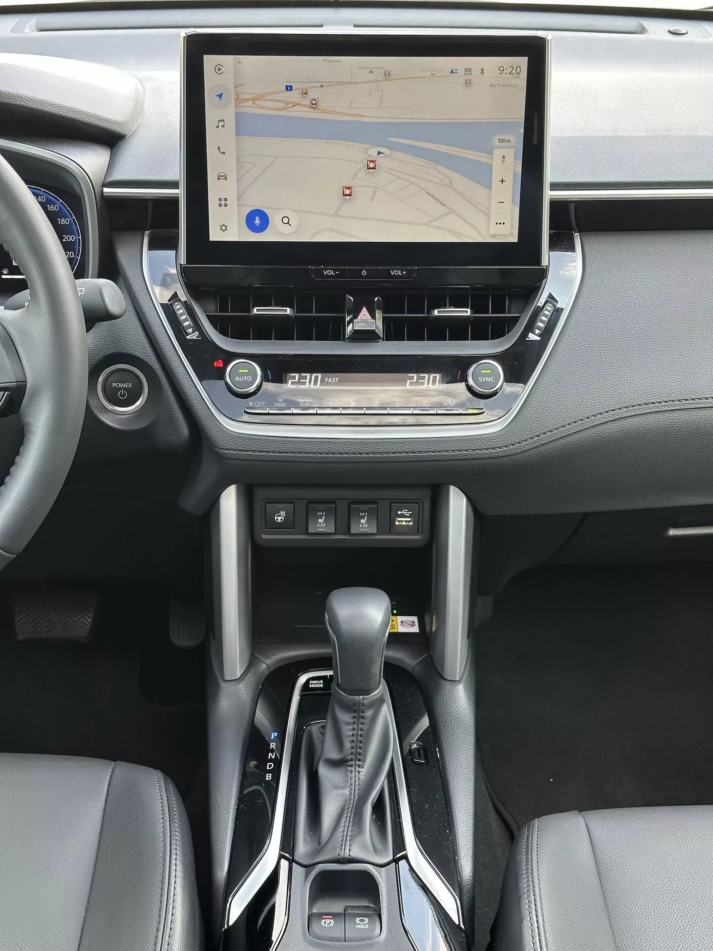 Notranjost Toyota Corolla Cross 2022 s sistemom na dotik infotainment z GPS navigacijo, dvo-conskim nadzorom podnebja, režo za CD, gumbi za upravljanje medijev in telefona, moderna avtomatska prestavna ročica in usnjenimi poudarki na sredinski konzoli in oblikovanju armaturne plošče