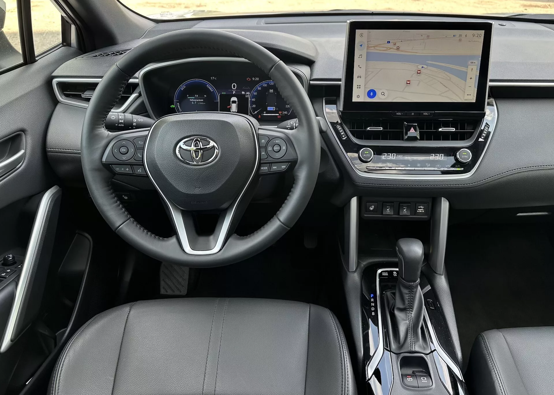 Notranjost Toyota Corolla Cross 2022 iz perspektive voznika, ki prikazuje volan, instrumentno ploščo, sredinsko konzolo in sedež sopotnika