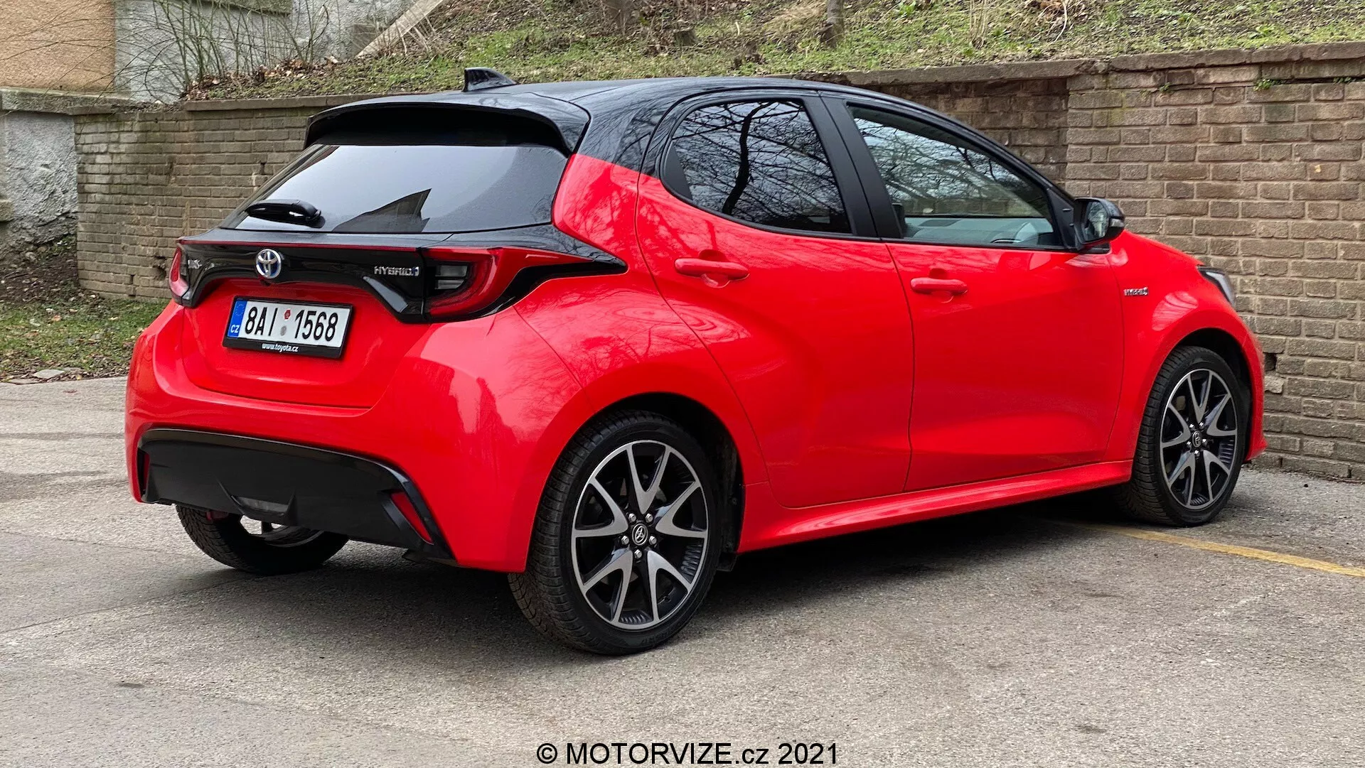 Trikrat četrtinski zadnji pogled na svetlo rdeč, moderen hatchback z ostrimi linijami in gubami, strešnim spojlerjem, LED zadnjimi lučmi, anteno v obliki plavuti morskega psa, večkrakimi platišči iz lahke zlitine, in parkiran na parkirišču z odbojno, dobro vzdrževano barvo, kar nakazuje nov ali dobro vzdrževan model v športni različici.