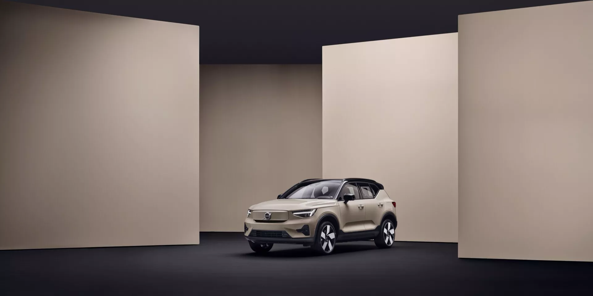 Volvo EX40 letnik 2024 1. generacije v krem barvi predstavljen v studiu s kontrolirano osvetlitvijo, ki poudarja njegov eleganten dizajn, LED žaromete, značilno masko in sodobne tehnološke funkcije