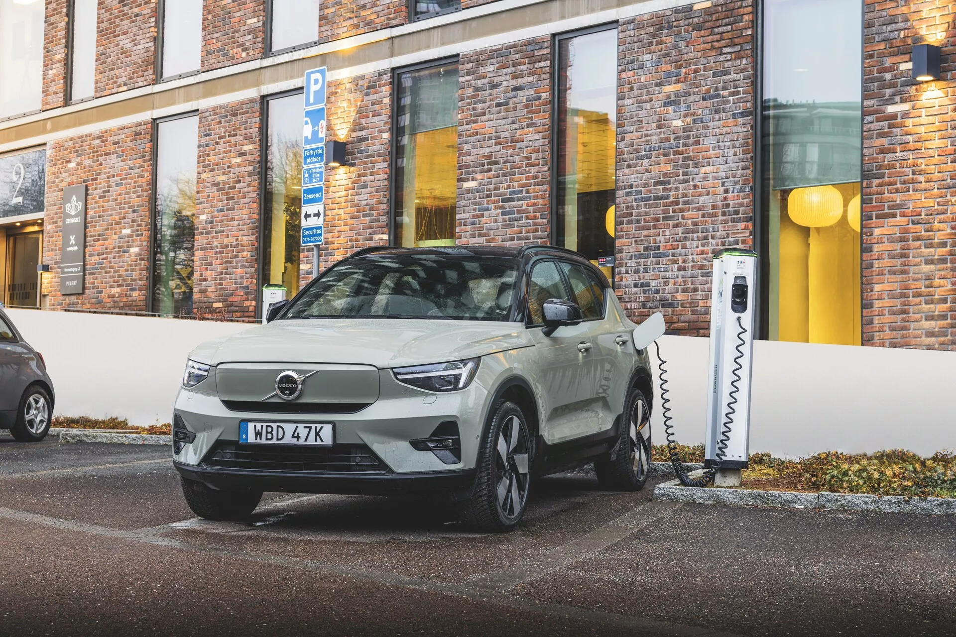 Električno vozilo Volvo EX40 1. generacije letnik 2024, parkirano pod kotom, ki izkazuje elegantno zasnovo in tehnološke značilnosti kot so LED luči in polnilni vhod, v urbanih okoljih
