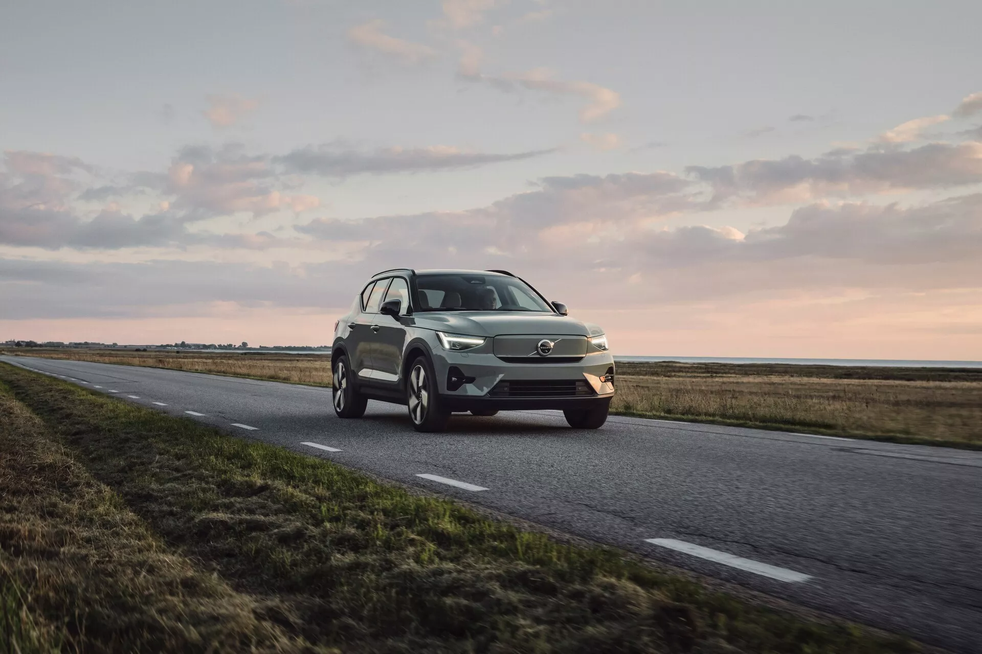 Volvo EX40 2024 1. generacije v dinamičnem pogledu s treh četrtin spredaj, ki prikazuje LED žaromete, značilno masko, lita platišča in sodobno zasnovo SUV v kovinski barvi pod mehko naravno svetlobo