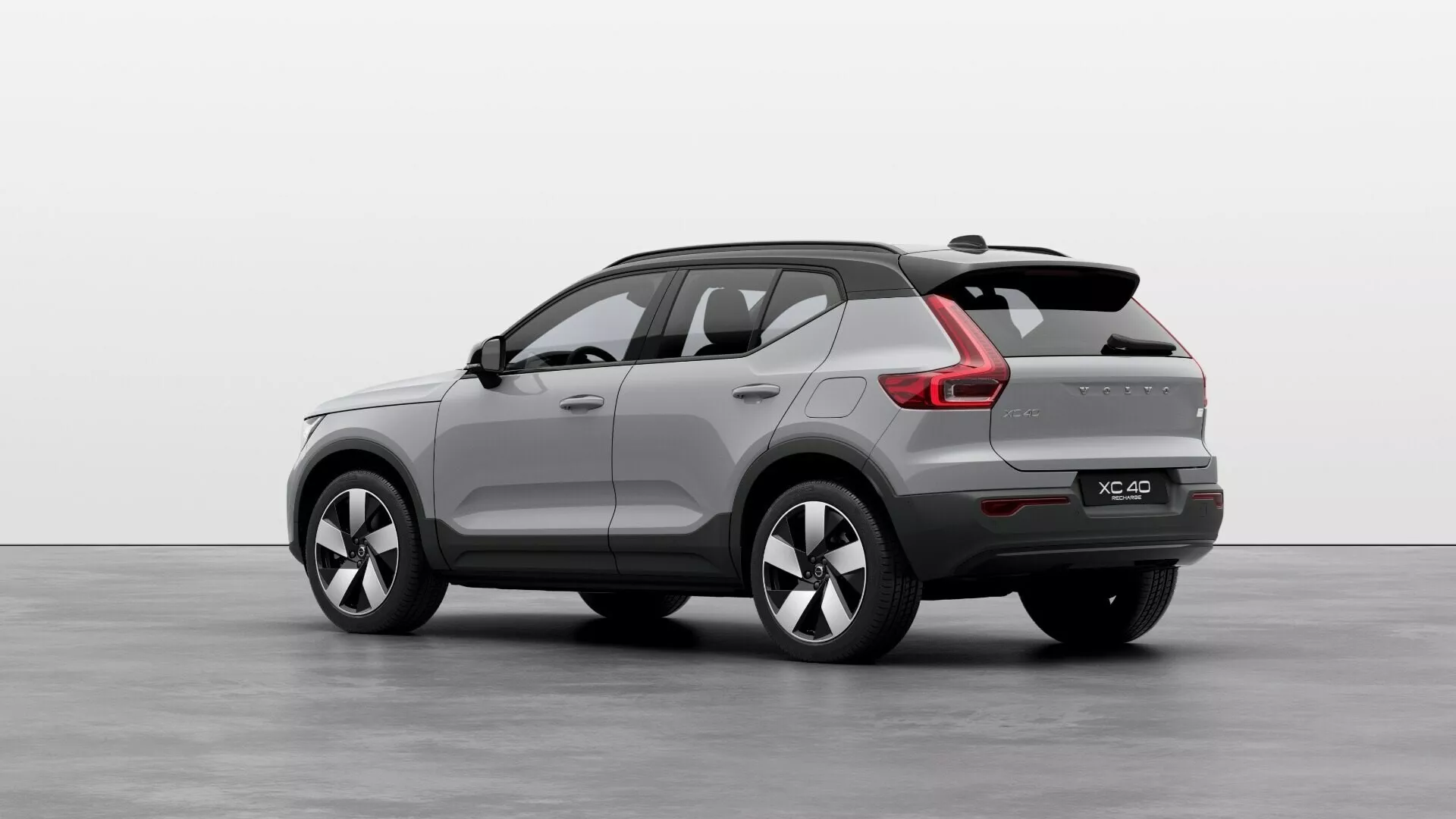 Volvo EX40 prve generacije letnik 2024 v trčetrtem zadnjem pogledu prikazuje kompaktno do srednje veliko karoserijo SUV-ja, športno padajočo zadnjo streho, integriran zadnji spojler, LED zadnje luči z modernim podpisom svetlobe, dvojne izpušne cevi, večkraka lita kolesa in stranska ogledala z integriranimi smerokazi v studijskem okolju.