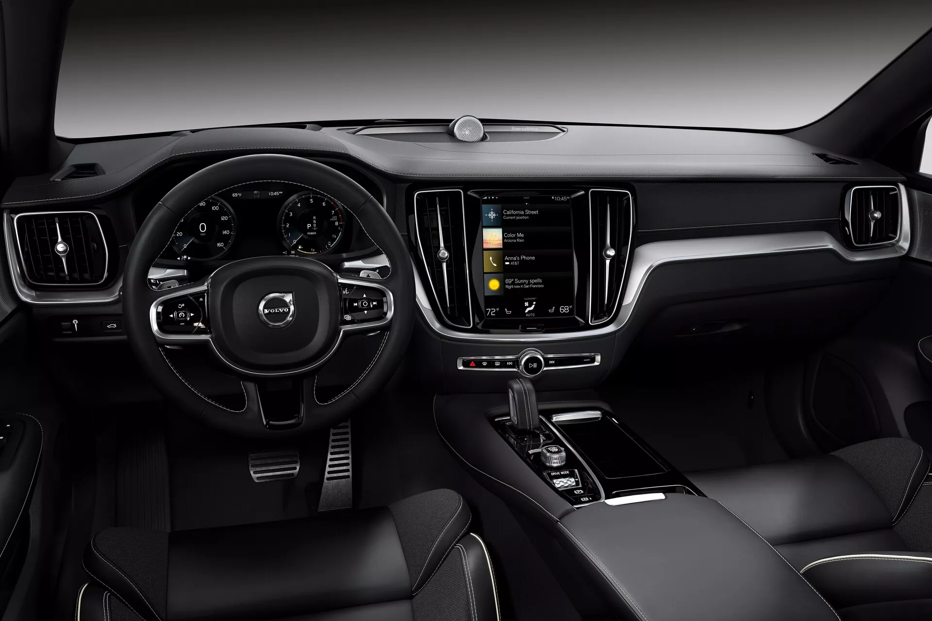 Notranji pogled automobila Volvo S60/V60 2018 (3. generacija) iz voznikove perspektive. Slika se osredotoča na moderno, tehnološko napredno armaturno ploščo s trokrakim večnamenskim volanom, delno vidnim digitalnim instrumentom in navpično usmerjenim zaslonom na dotik za informativno-razvedrilni sistem. Notranjost je izdelana iz usnja ali usnju podobnih materialov s kovinskimi detajli in vključuje panoramsko streho, kar odraža razkošno in inovativno oblikovanje notranjosti avtomobila.