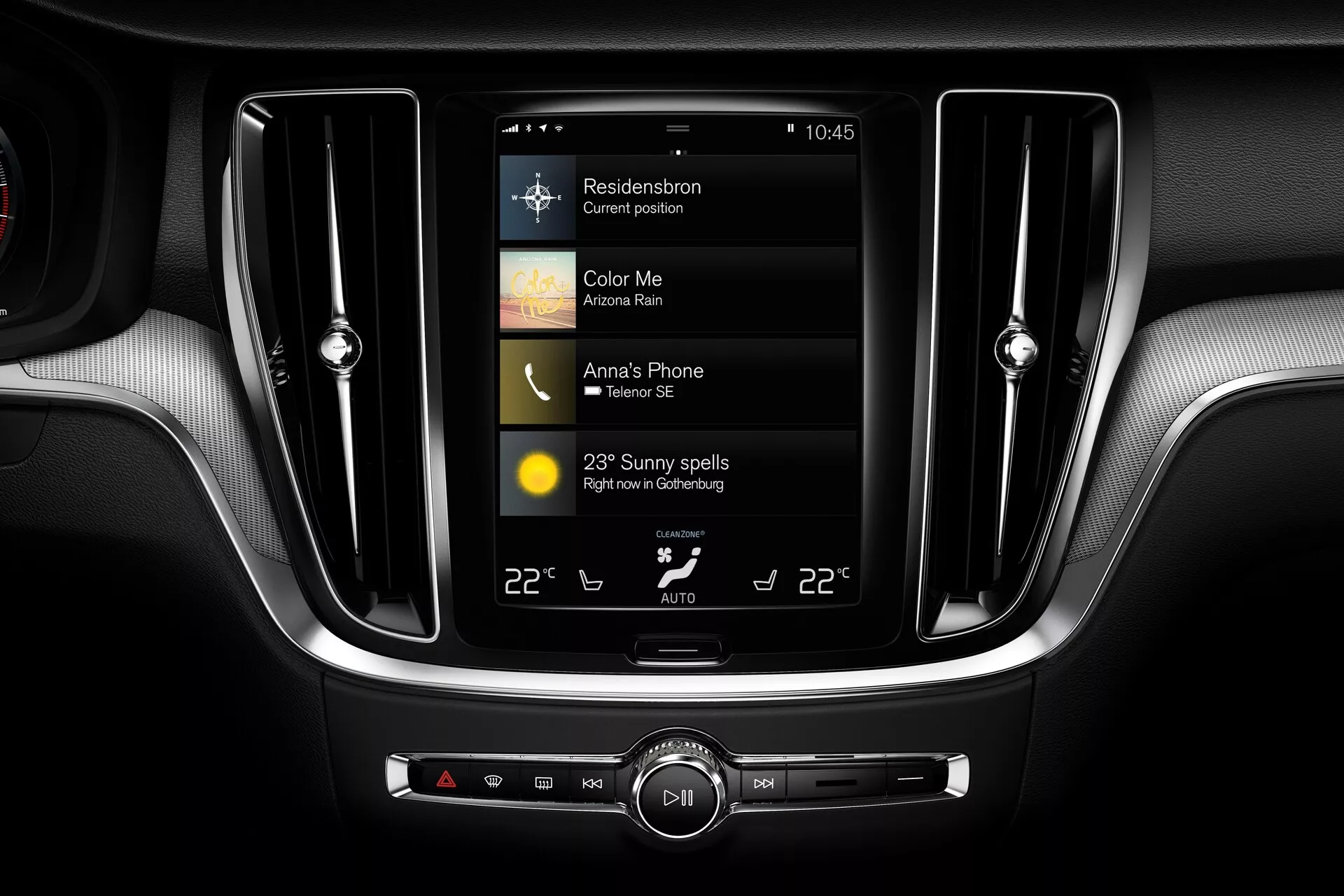 Podroben pogled na osrednjo konzolo zdajšnjega avtomobila Volvo S60/V60 2018 (3. generacija), ki izpostavlja navpično urejen zaslon na dotik infotainment sistema, ki prikazuje informacije o navigaciji, medijih in vremenu, obdano z zračniki s kromiranimi zaključki in dvopodročno klimatsko napravo s premium dvobarvno armaturno ploščo.