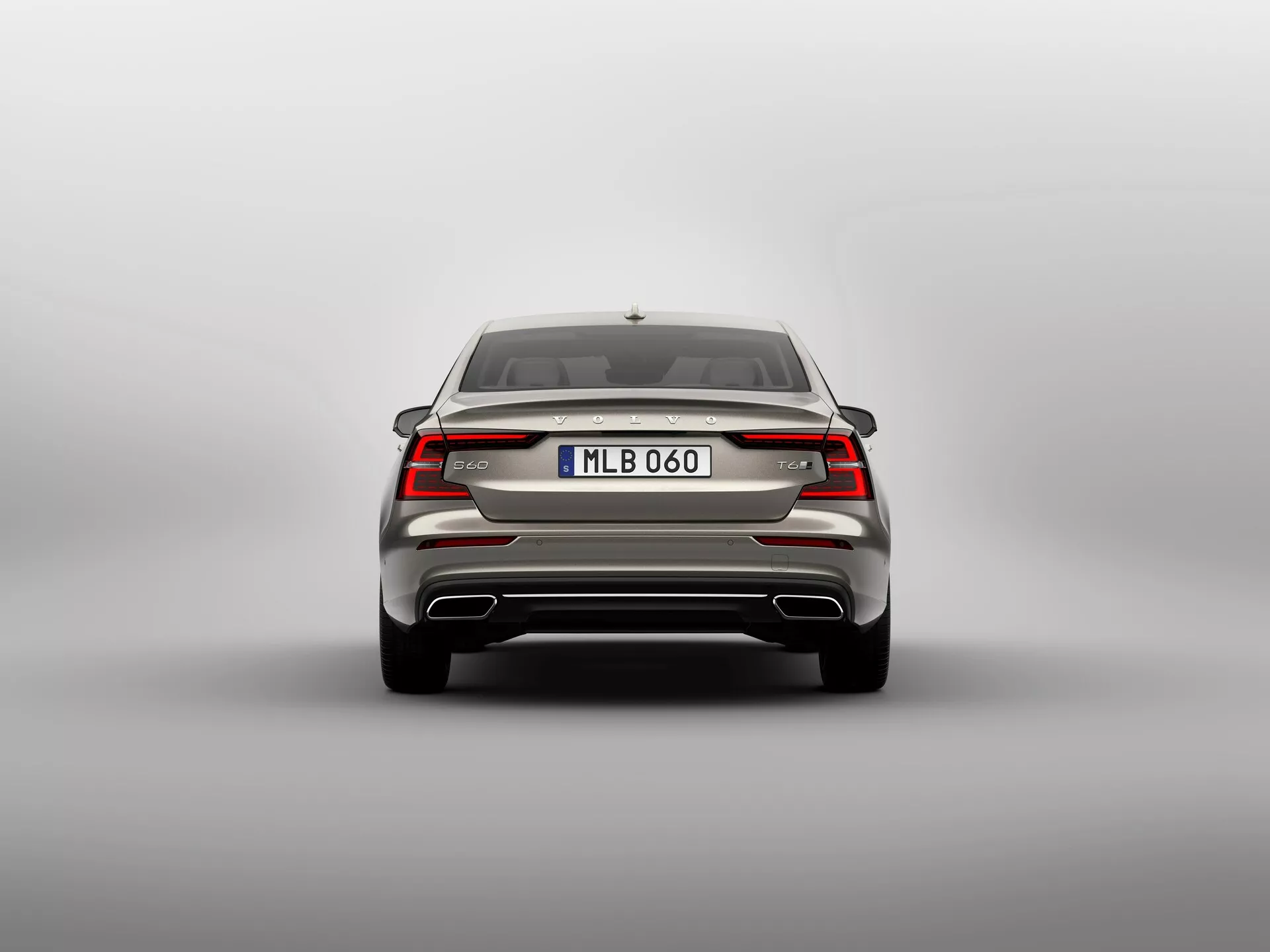 Zadnji pogled na sodoben 2018 Volvo S60-V60 tretje generacije, ki prikazuje simetrično zasnovo z elegantnimi vodoravno usmerjenimi LED zadnjimi lučmi, ki se srečujejo pri emblemati znamke, vgrajenim spojlerjem v prtljažniku, robustnim zadnjim odbijačem z odsevniki in verjetno parkirnimi senzorji, oznako modela, evropskim registrom in možno zadnjo kamero, dvojnimi izpušnimi cevmi, antensko reko in zadnjim oknom s vgrajenim odmrzovalnikom, posnet z naravnega pogleda v višini oči proti nevtralnemu ozadju.