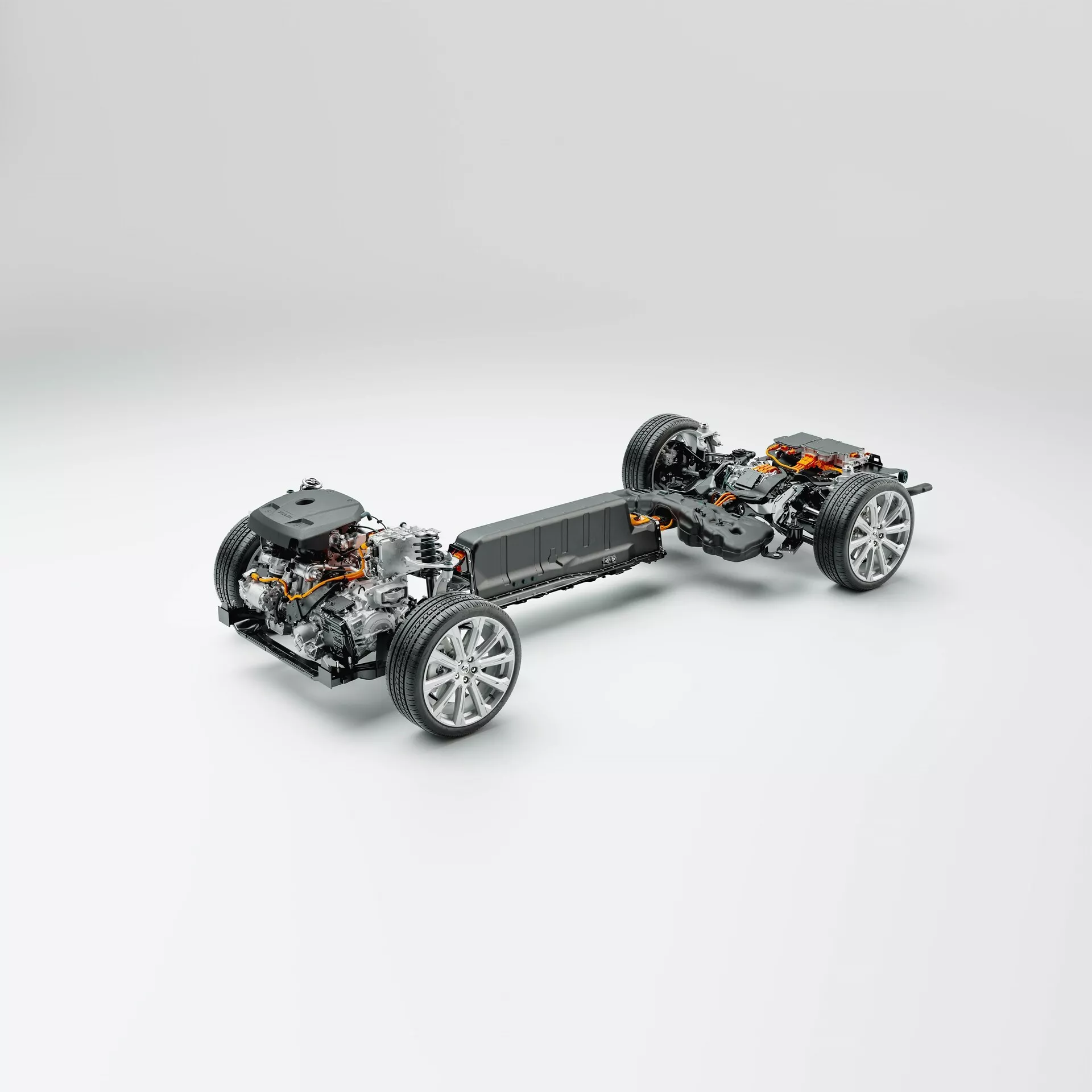 Tretročetrtinski pogled od zgoraj navzdol na platformo vozila Volvo XC60 2021 (druga generacija, preoblikovanje) brez zunanjih panelov, ki prikazuje šasijo, pogonske in vzmetne komponente. Vozilo je centrirano na nevtralnem, svetlo sivem ozadju. Sprednji del avtomobila je na dnu, rahlo obrnjen v levo, kar omogoča jasen pogled na sprednja kolesa in vzmetenje. Podroben pogled na krmilni mehanizem, zlitinska platišča športnega tipa in zavorne komponente. Osrednji del razkriva paket baterij, kar nakazuje, da je to platforma za električna vozila (EV), integrirana v tla za nižje težišče. Za baterijskim paketom so vidne električni motor in pogonske komponente, kar nakazuje pogon na zadnji kolesi ali na vsa kolesa. Zadaj so kolesa opremljena s podobnimi vzmetnimi in zavorni komponentami. Ta slika je še posebej primerna za kategorije, kot so avtomobilska tehnologija, električna vozila, mehansko inženirstvo in dizajn vozil.
