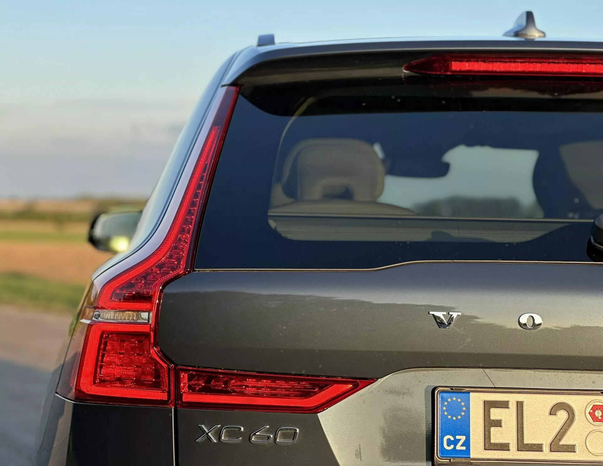 Volvo XC60 Recharge plug-in hibrid 2021, ki podnevi v naravni svetlobi pokaže elegantno zasnovano LED zadnjo luč, oznake AWD in značilne zunanje lastnosti