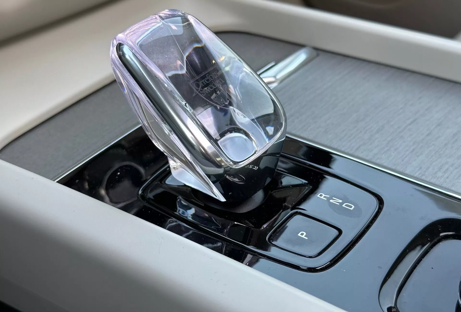 Pogled od blizu notranjosti Volvo XC60 Recharge Plug-in Hybrid 2021 z osredotočenjem na visokotehnološko elektronsko prestavno ročico in občutljive na dotik nadzorne plošče