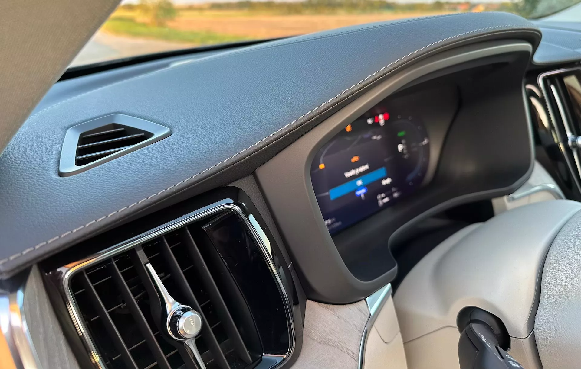 Notranji pogled Volvo XC60 Recharge Plug-In Hybrid 2021, ki prikazuje armaturno ploščo s poudarkom na naprednem digitalnem instrumentnem zboru in materialih visoke kakovosti iz perspektive sovoznikovega sedeža.