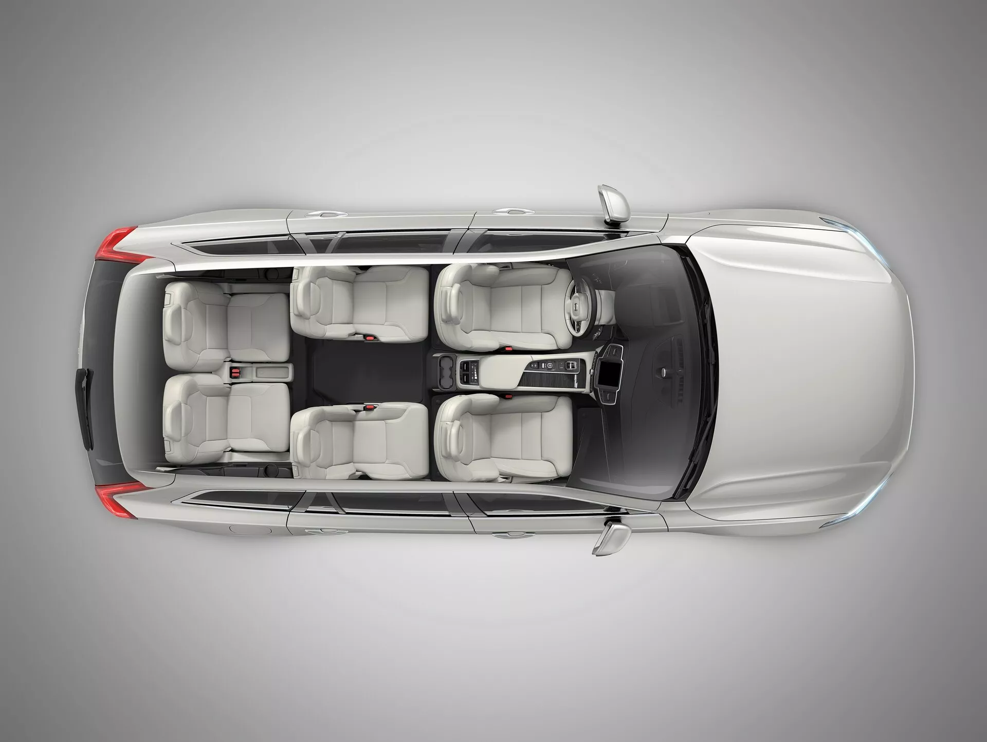 Pogled od zgoraj na Volvo XC90 2015 (2. generacija), ki kaže srebrno kovinsko sivo zunanjost, štirivratno karoserijo SUV, okna s UV zaščito, notranjo postavitev za sedem sedežev z svetlo sivimi sedeži in platišča iz lahke litine. Slika poudarja naslednje ugotovljene funkcije: ADAS, varnost vozila, informacijsko-razvedrilni sistem, večpodročno klimatsko napravo, brezključno vstopanje in parkirne asistence, s studijski osvetlitvijo, ki zagotavlja jasen poudarek na podrobnem oblikovanju avtomobila.