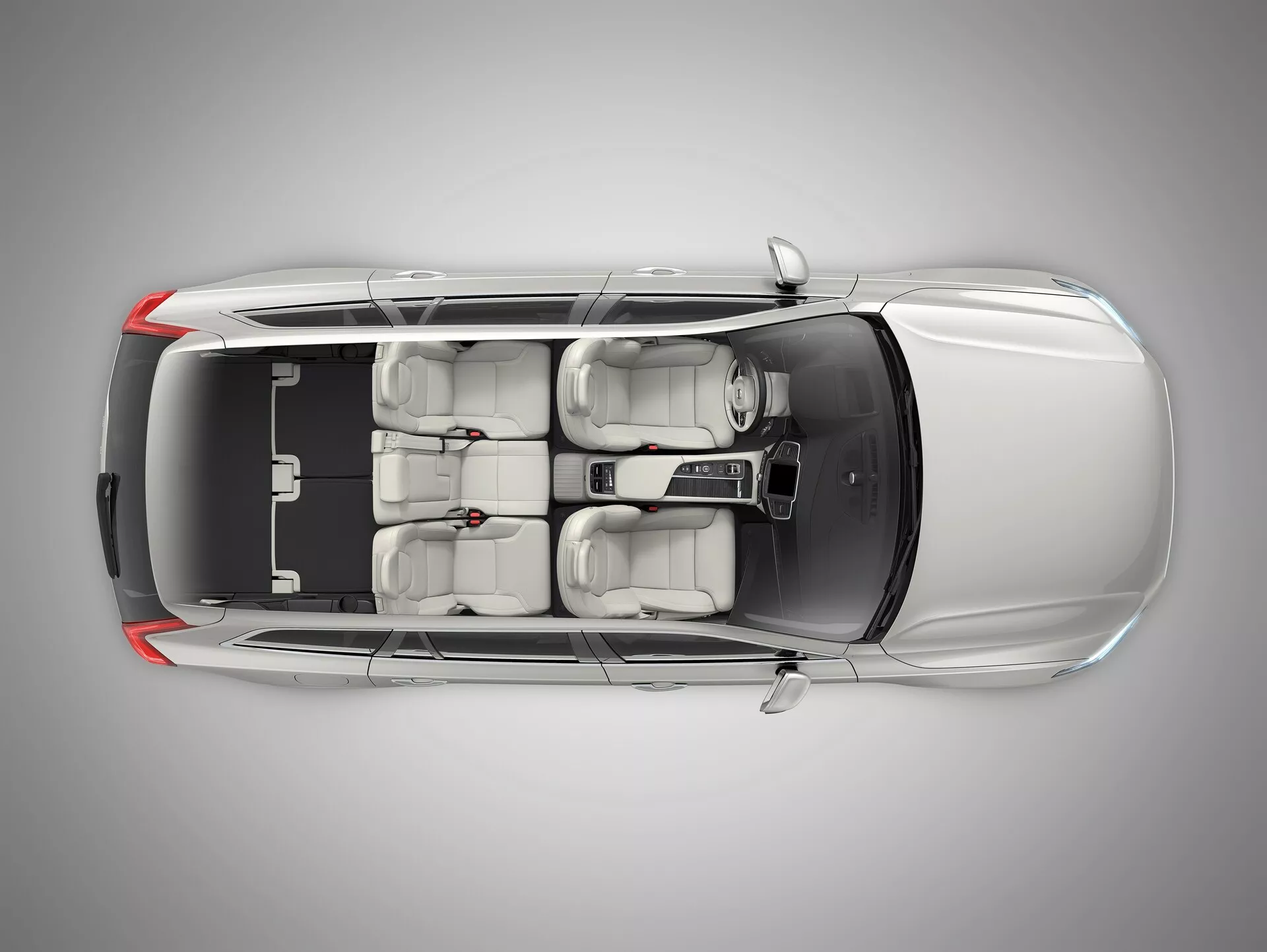 Pogled z zgoraj na kovinski Volvo XC90 2015 s kontrastno črno streho, aerodinamičnim dizajnom, strešno okno, dvema vrstama sedežev z naprednimi nastavljivimi sprednjimi sedeži, centralno krmilno konzolo in zatemnjenimi okni, postavljen v profesionalnem studiu.