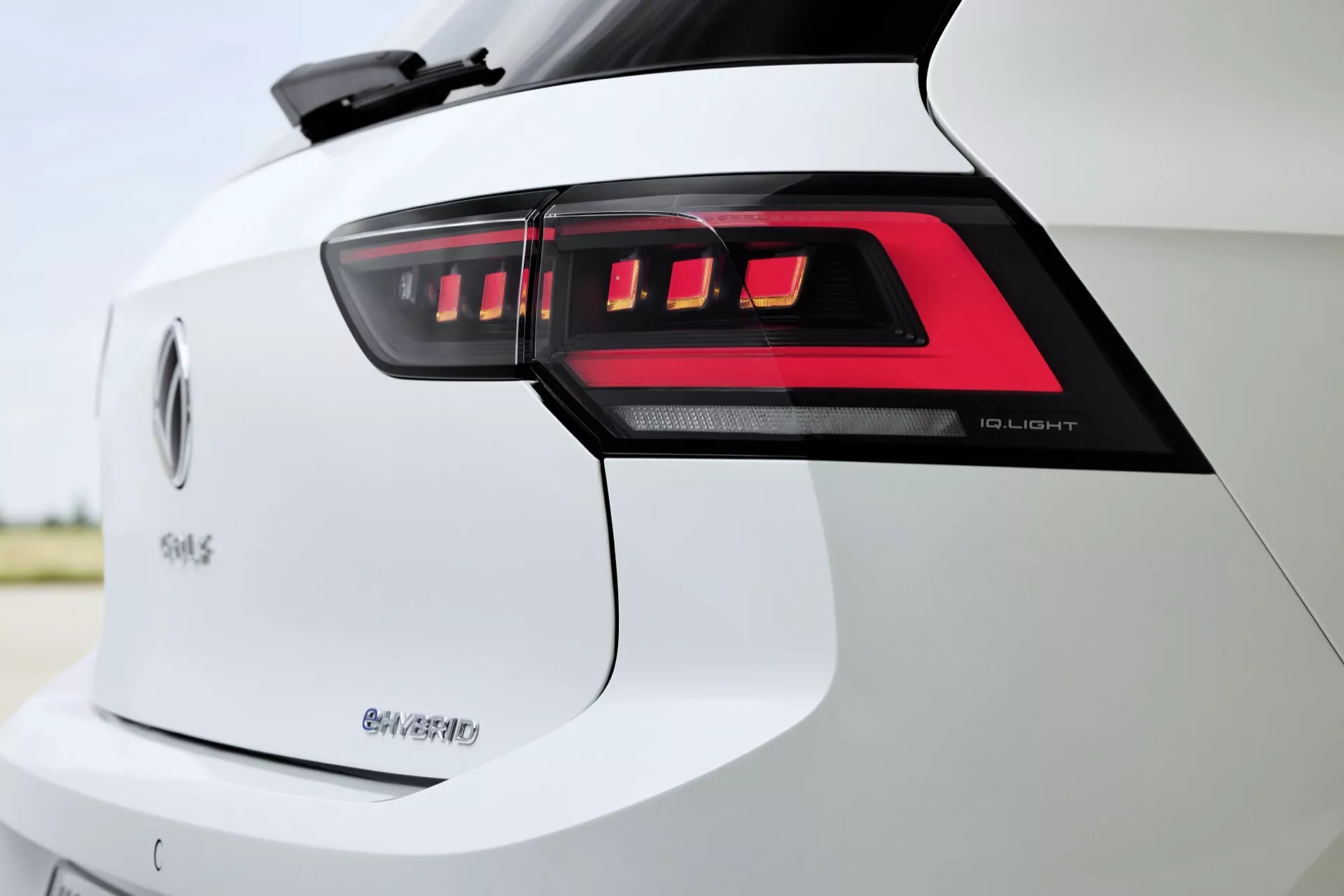 Podroben posnetek zadnjega dela VW Golfa 2024 (VIII-facelift) z LED zadnjimi lučmi, oznakami '50 e-tron' in 'Q4', ki poudarja napredno LED svetlobno tehnologijo, električno mobilnost in potencialne zmogljivosti pogona na vsa kolesa v beli zunanji barvi.