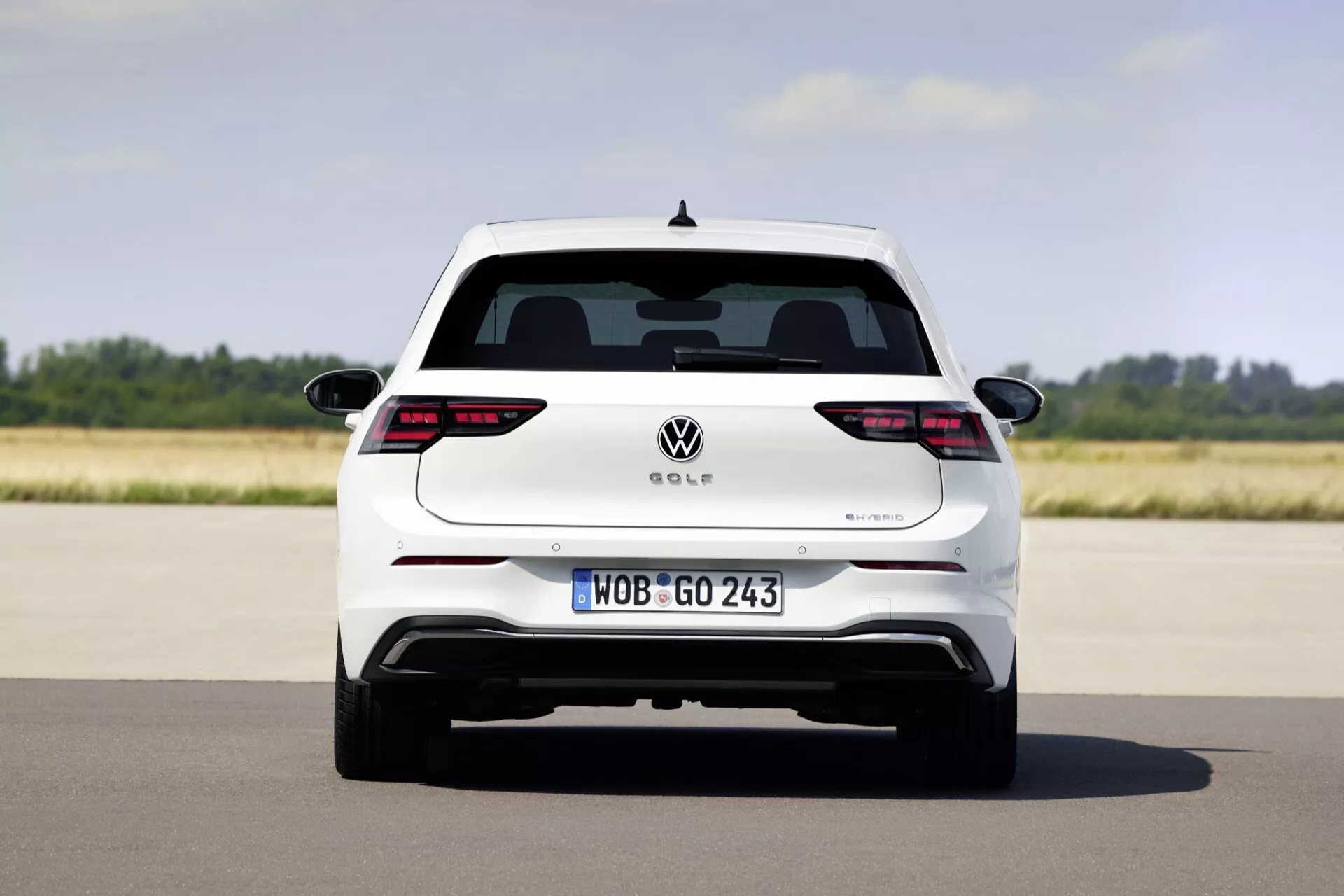 Pogled od zadaj na Volkswagen Golf VIII facelift 2024, ki prikazuje celotno širino in elemente oblikovanja, kot so LED zadnje luči, evropska registrska tablica in morebitni hibridni izpušni sistem na odprti cesti.