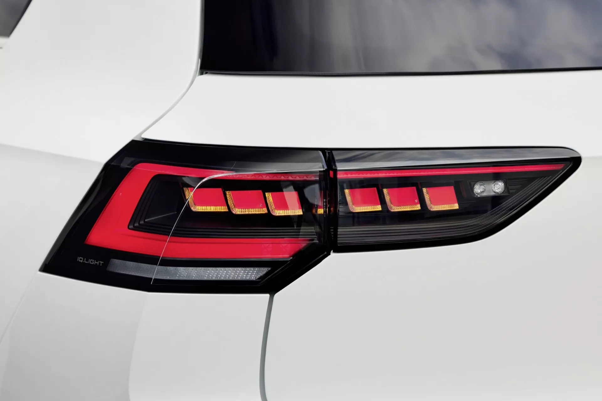 Posnetek desne zadnje luči VW Golf VIII facelift 2024, ki prikazuje horizontalne LED segmente in OLED tehnologijo na belem vozilu