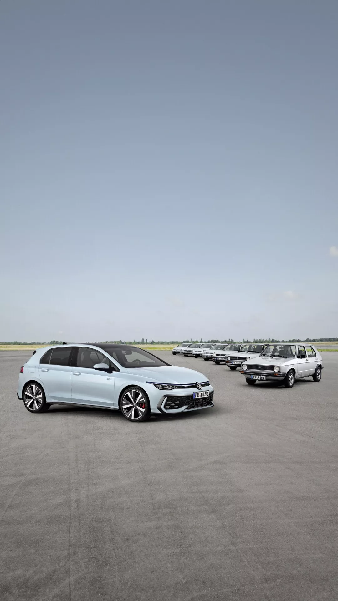 Pogled od spredaj in s strani na VW Golf VIII prenovljeno različico 2024 na odprtem parkirišču, ki poudarja oblikovalske elemente, kot so LED žarometi, lita kolesa in napredne varnostne funkcije, z vrsto avtomobilov v ozadju pod jasnim nebom.