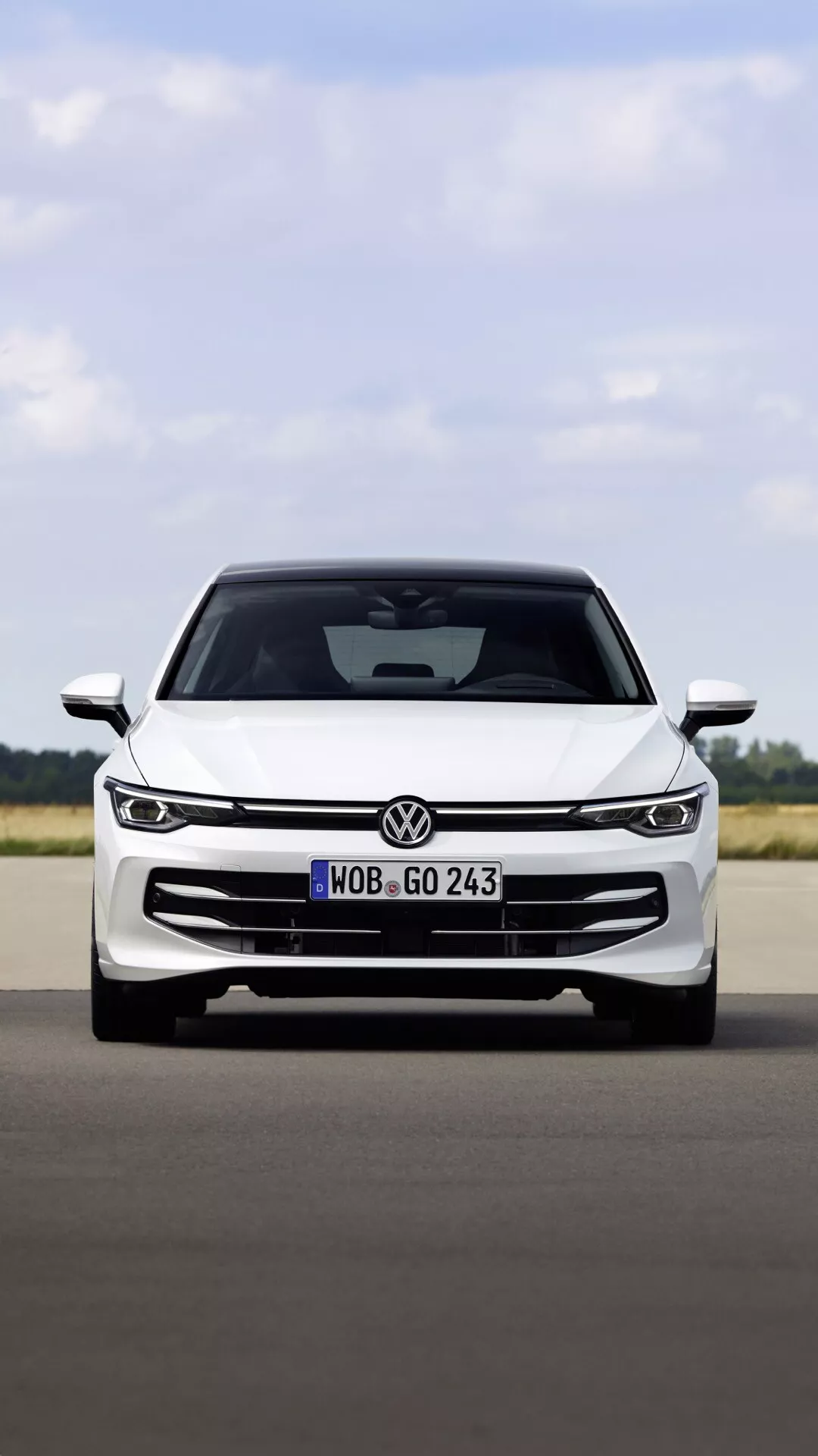 Sprednji pogled na VW Golf (VIII Facelift) 2024 na utrjeni površini, prikazuje njegovo rešetko, elegantne LED žaromete, emblem in aerodinamično obliko pokrova, kar nakazuje na moderno tehnologijo in športno estetiko.