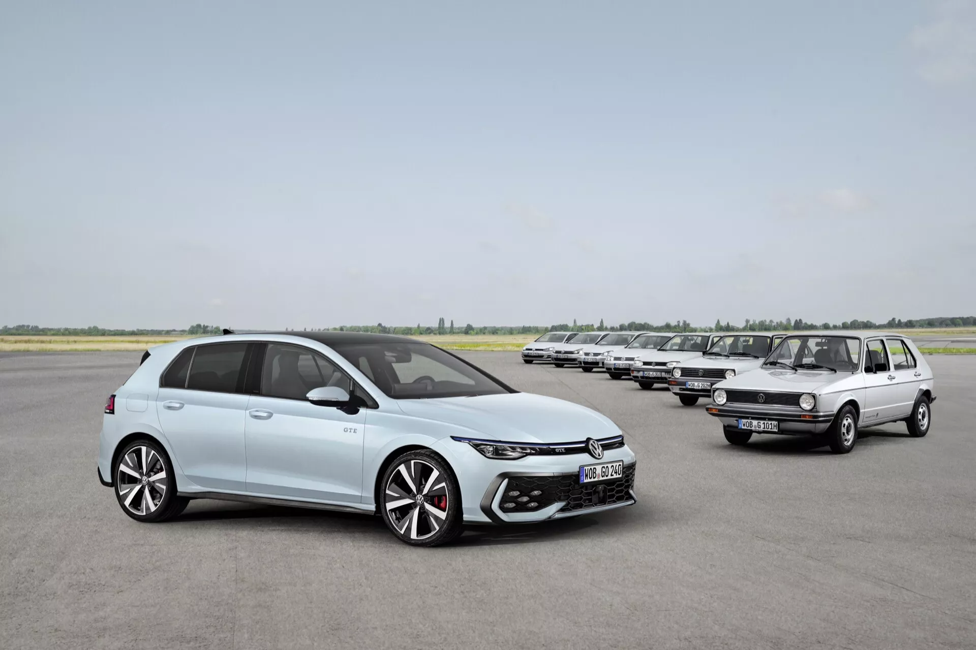 VW Golf 2024 (VIII-Facelift) v svetlo modri, sodobna hatchback zasnova z LED žarometi, velikim zračnim vhodom, 18+ palčnimi dvobarvnimi aluminijastimi platišči in elegantnimi linijami karoserije, ki prikazuje razvoj avtomobilskega oblikovanja ob starejšem modelu VW Golf na vzletno-pristajalni stezi.