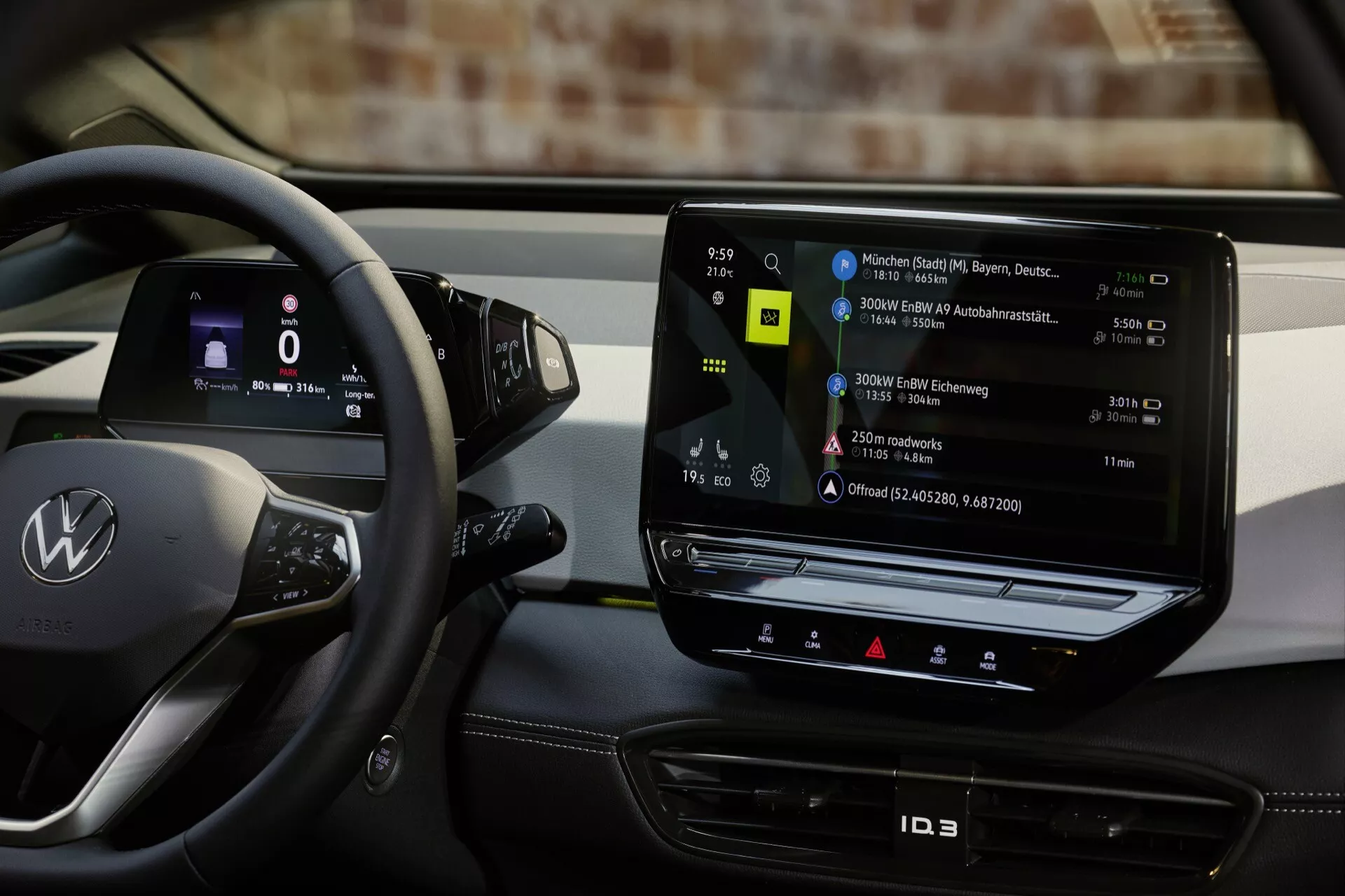 Notranji pogled na Volkswagen ID.3 letnik 2023, ki prikazuje stran voznika z volanom, logotipom, kontrolnimi gumbi in izstopajočim navpičnim zaslonom na dotik infotainment sistema, ki prikazuje zemljevid polnilnih postaj, odsevajoč sodobno tehnologijo električnih vozil.