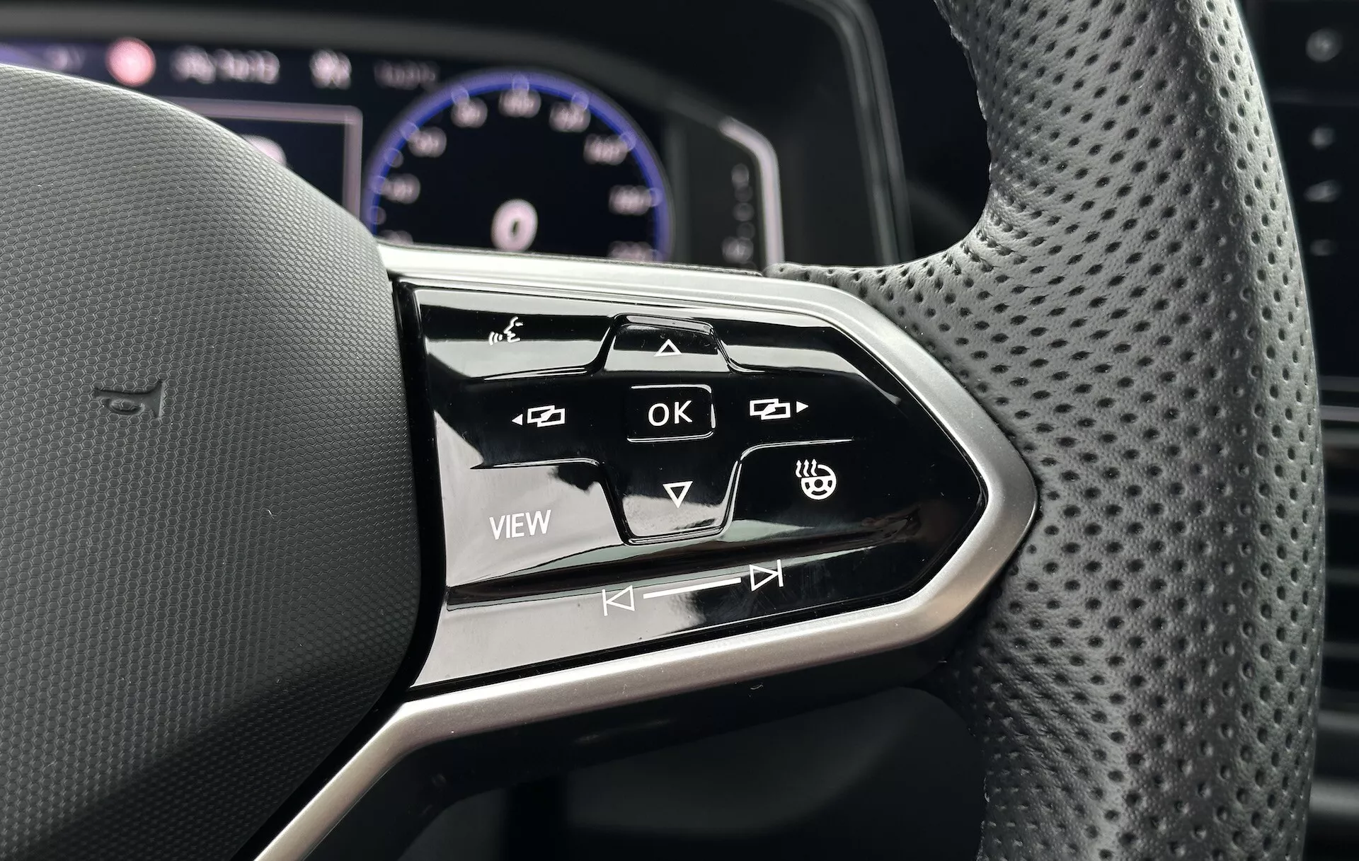 Približek multifunkcijskih kontrol na volanu VW T-Roc Cabriolet 2022, ki prikazuje ergonomsko oblikovanje in interaktivne gumbe za infotainment sistem in nastavitve vozila